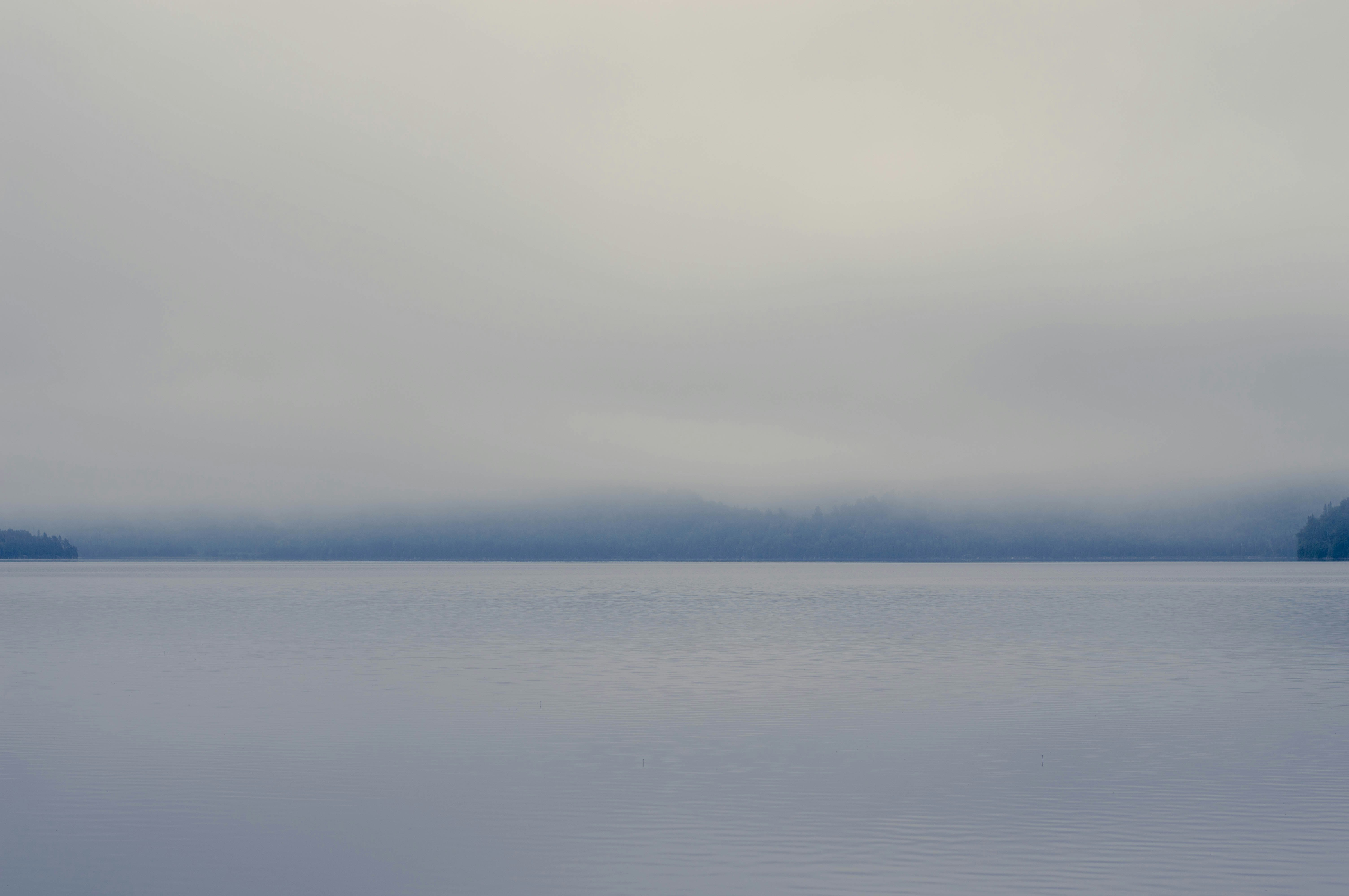 body of water under white clouds during daytime